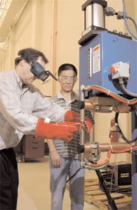 Dr. Mark Barkey, an associate professor of aerospace engineering and mechanics, and Guoaing Wang spot weld specimens to evaluate their strength. 