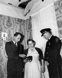 Ed Howard, then Sylacauga mayor, Ann Hodges and then Sylacauga Police Chief W.D. Ashcraft pose with a meteorite underneath the point where it crashed through Hodges' house in 1954. Hodges donated the meteorite to UA's Alabama Museum of Natural History in 1956. 