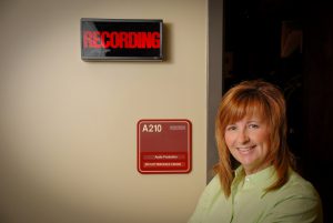 Rock stands outside the Faculty Resource Center's audio production suite. Her development of the Virtual Bug in Ear has potential in the educational, health care and corporate training fields. 