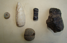 These five artifacts are among the several thousand recovered from the site of a 16th Century Cuban village during joint U.S. Cuban archaeological excavations during the last two summers. Two of these artifacts (top row, right) are examples of unfinished "idolillos," or little idols. These human-shaped figurines were produced at the site and worm by elite members of the group as part of a necklace. (Photo by Brooke Persons) 