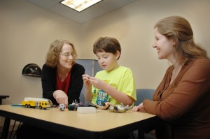 Dr. Laura Klinger, left, associate professor of psychology and director of UA's Autism Spectrum Disorders Clinic, and Dr. Sarah O'Kelley, far right, work with a child during an evaluation in the clinic. The magnitude of students entering college world-wide with an Autism Spectrum Disorder is said to be a testimony to the success of early intervention programs. (Laura Shill)