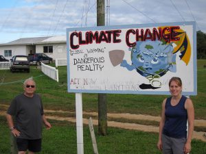 Dr. Paul Aharon and Hillary Sletten beside a billboard in front of the Niue Meteorological Service station. (Photo by Joe Lambert) 