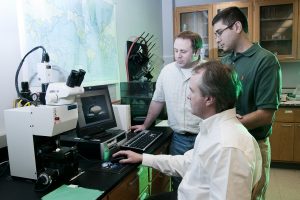Andrus, sitting, and, from left, Dr. Joe Lambert, environmental isotopes specialist, and Etayo-Cadavid work in a UA lab. 