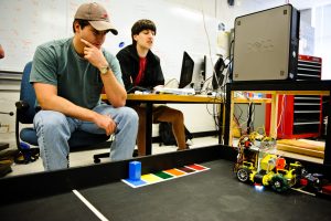 Team members Corey Dean, left, and Matthew O'Brien work with a robot in space provided for the team in Houser Hall. 