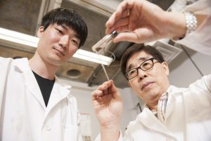 Hong, right, and UA doctoral student Jihoon Park display material in a vial. 