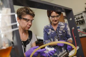 Drs. Gabriela Gurau, left, and Julia Shamshina work in a UA lab with an electrospinning apparatus (Jeff Hanson). 