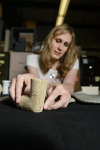 UA's Dr. Jera Davis examines a Copena engraved limestone pipe from Limestone County. 