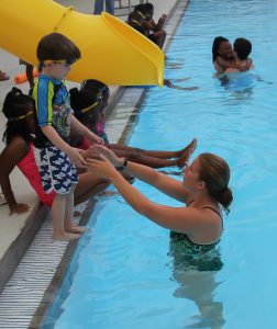 A sudent instructor helps a youngster take a step toward becoming a swimmer. 