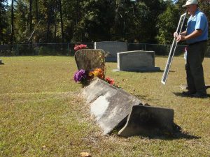 Brown uses a mirror to reflect sunlight, making it easier to read gravestone inscriptions.