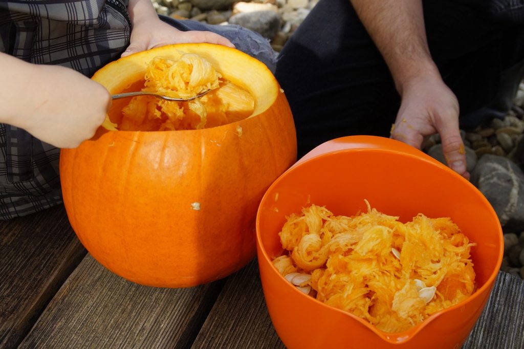 People cleaning out insides of pumpkins