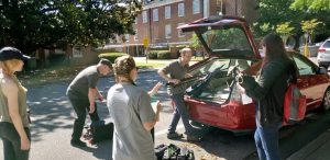 University of Alabama students and a professor place equipment into trunk of a car.