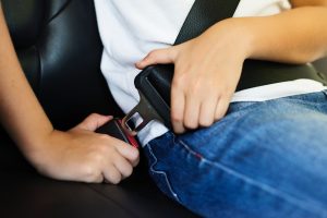A person buckles a seat belt inside a vehicle.