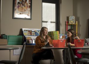 Two female graduate students sit at a table and discuss literacy research