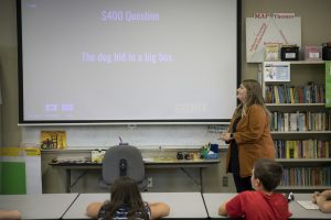 A female graduate student leads a literacy game with elementary children