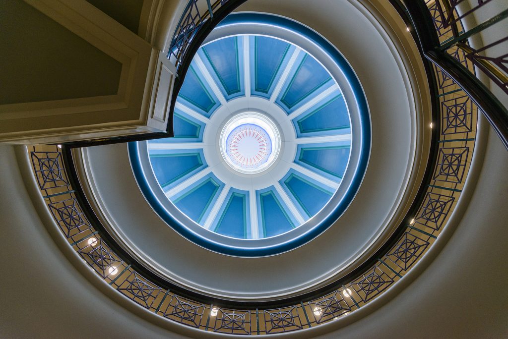 A decroative glass ceiling sits at the top of a spiral staircase.
