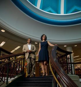 Business professors stand atop spiral staircase.