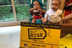 Two RISE students with a BUY for RISE sign.
