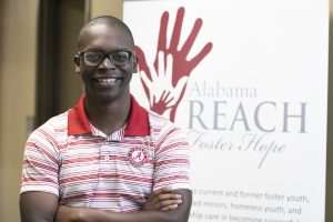 A male student poses for a photo in front of Alabama an REACH sign.