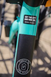 A green Gotcha e-bike at a bicycle rack.