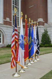 American flag lined up besides U.S. military flags