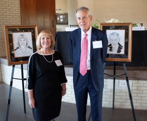 Deborah Land and Paul Vincent stand with their respective portraits.