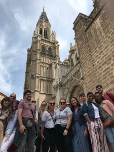 Group of UA students stand in front of a cathedral on a sunny day in Toledo, Spain 