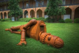 A sculpted robot lies on its side in the grass. 