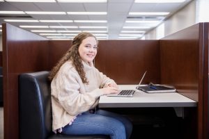 A female student uses a laptop while sitting at a study table. 