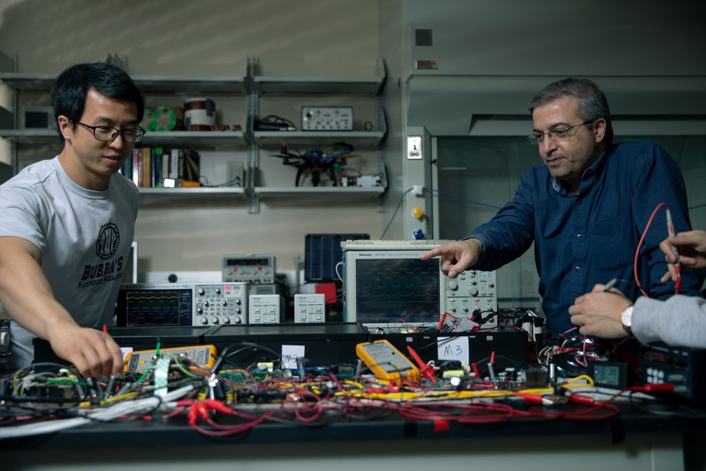 Two men work with electronic equipment on a table.