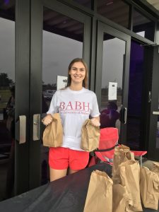 Abigail Gunter holding brown paper bags with free food