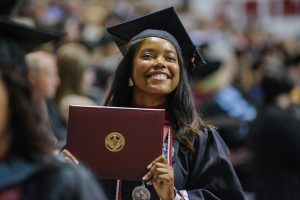 Woman smiles with her degree in hand. 