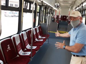 James Knickrehm stands inside a Crimson Ride bus showing bus seats marked off for social distancing