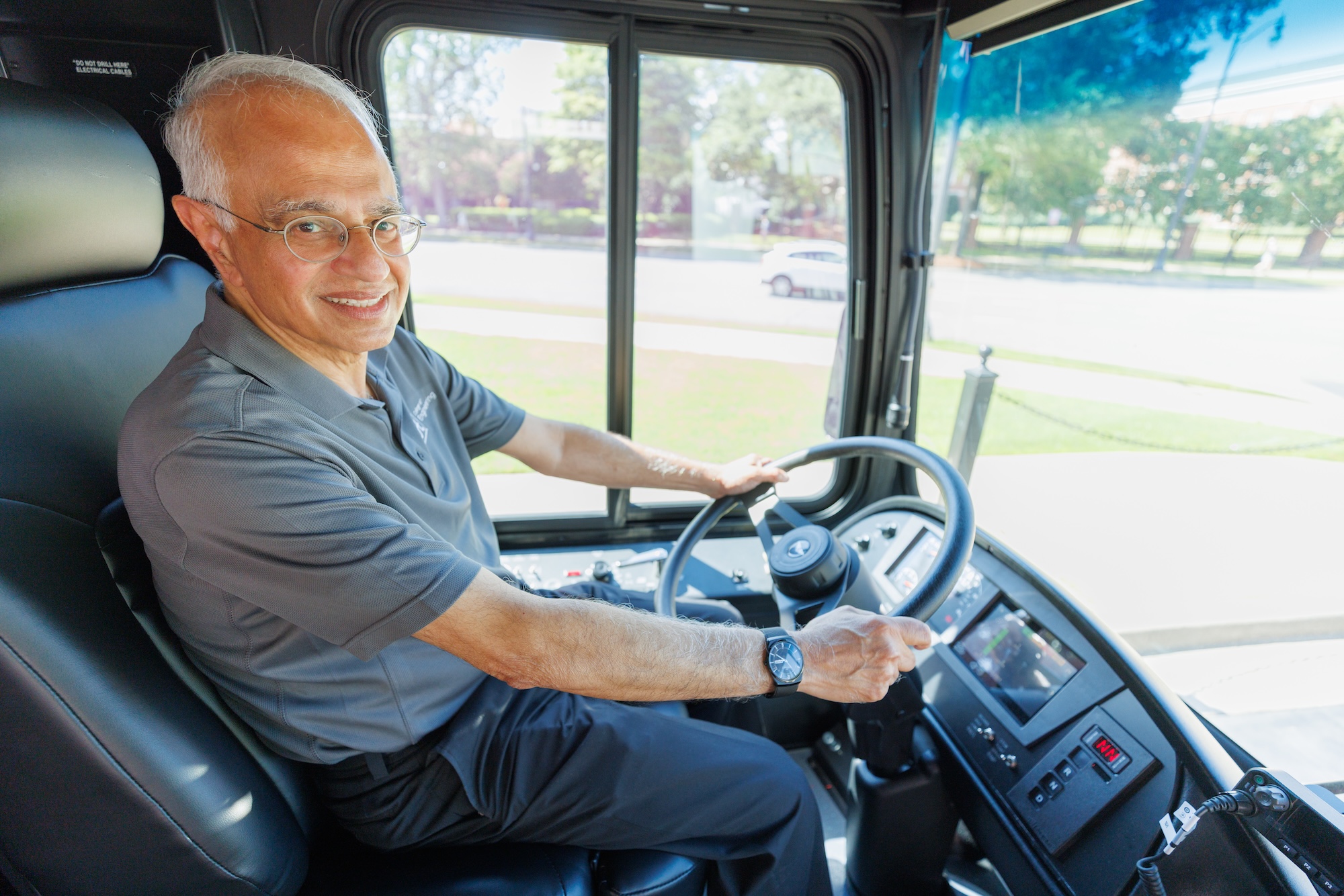 A UA engineering researcher smiles from the driver's seat of the bus.